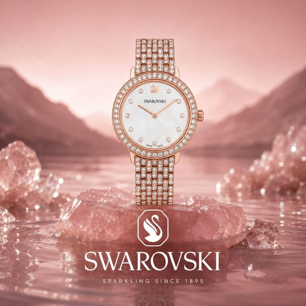 Swarovski-klocka i roséguld med kristaller mot rosa bakgrund.